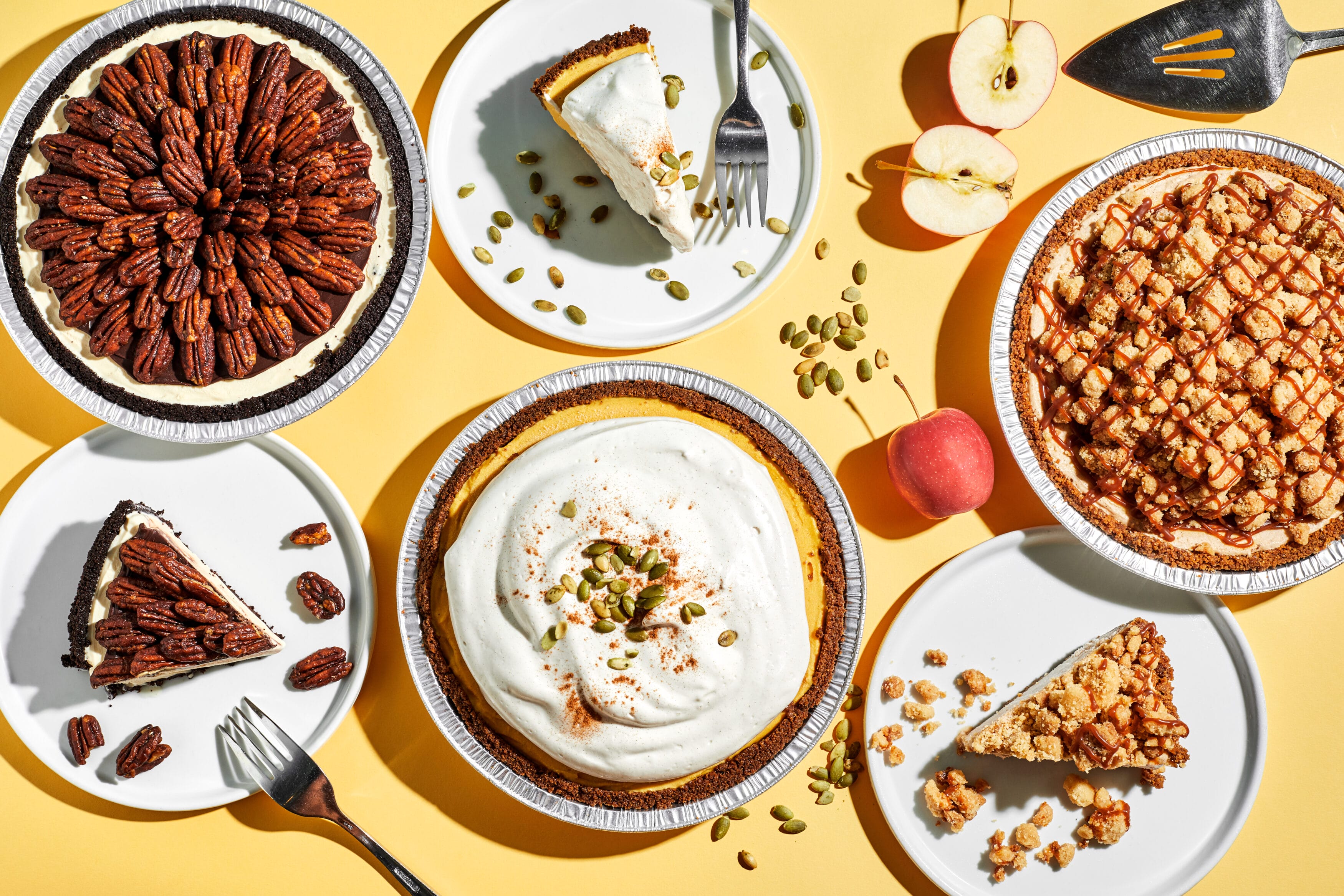 A spread of Thanksgiving ice cream cakes including Apple Pie, Pecan Pie, and Pumpkin Pie